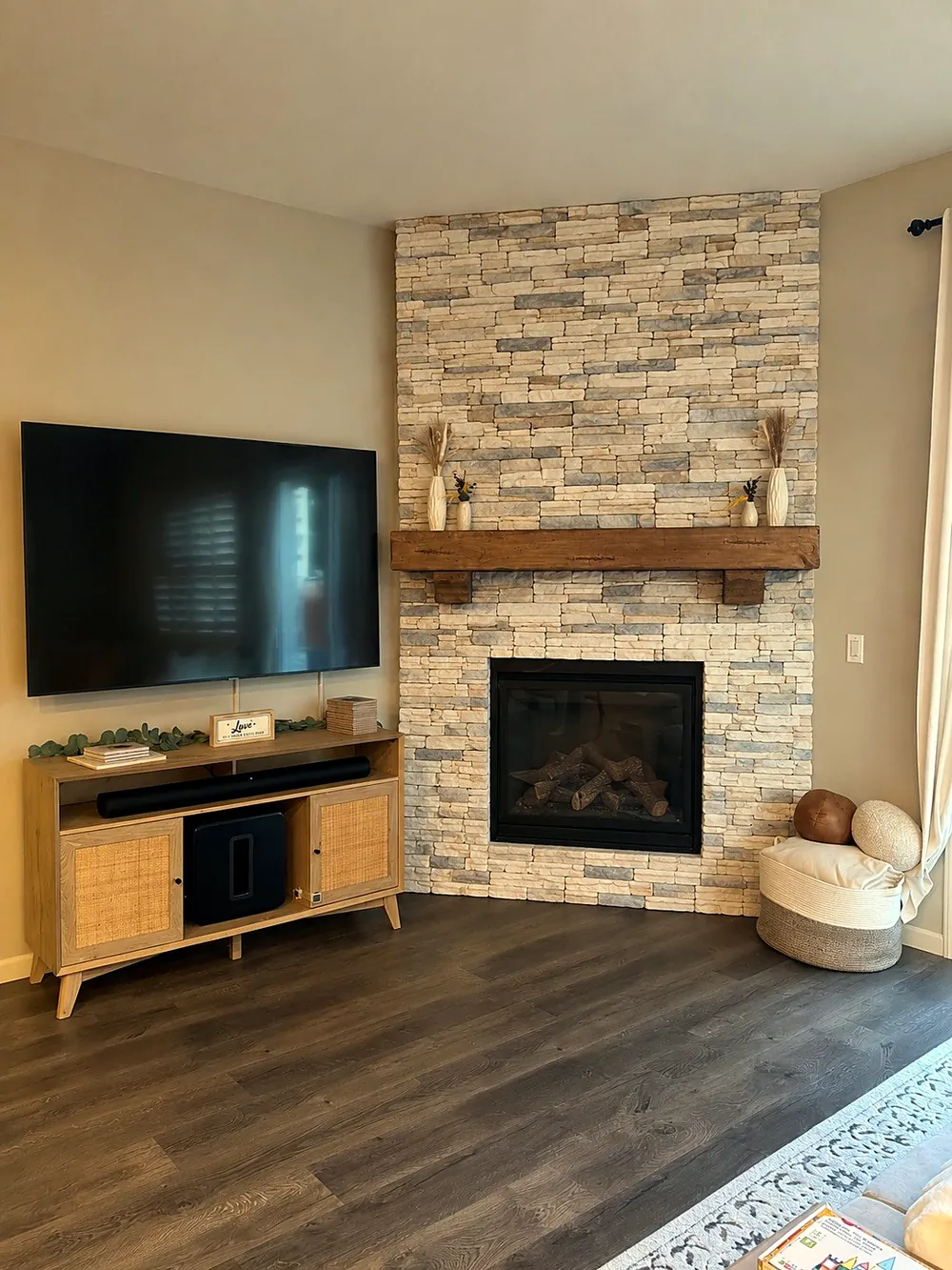 After: floor-to-ceiling stacked stone fireplace with wood beam mantel in the same room