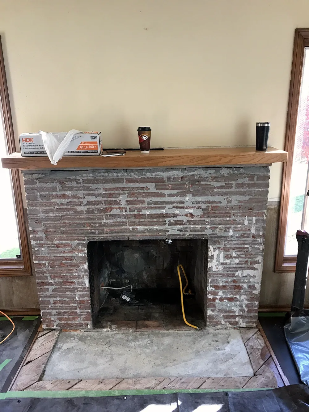 Before: worn brick fireplace with an open firebox and wood mantel