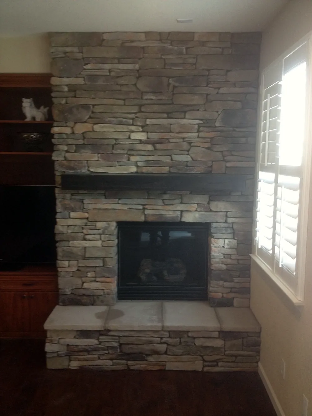 After: stacked stone fireplace to the ceiling with a mantel ledge and raised hearth