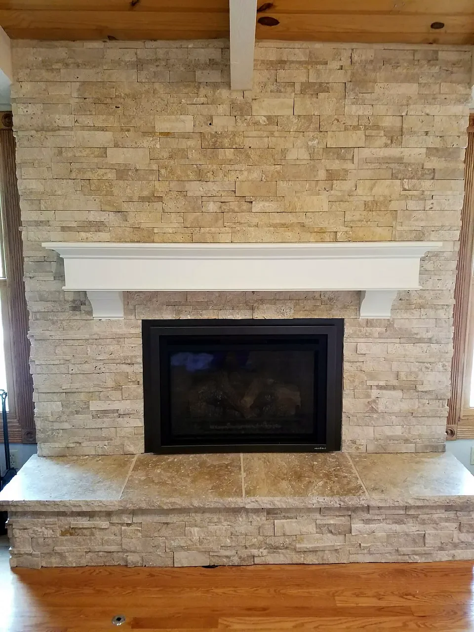 After: light ledgestone fireplace with a white mantel and stone hearth