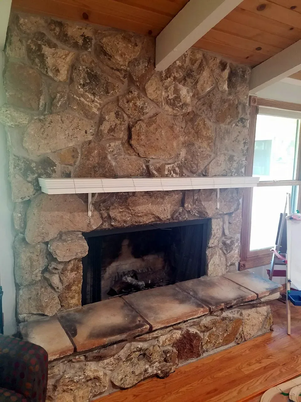 Before: old rough rock fireplace with a white mantel shelf